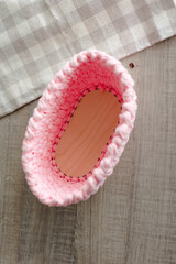 rectangular basket made of pink knitwear, on the table. white background