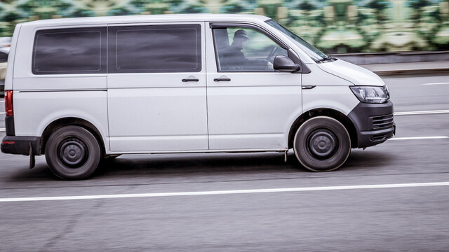 Fast moving Volkswagen Transporter T6 on the city road. White van rides on street. Commercial auto in fast motion with blurred background. speeding in the city concept