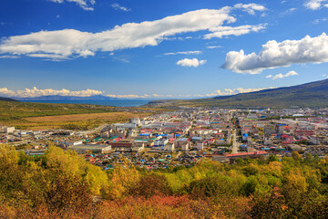 Scenic autumn city landscape. Top view of the city of Magadan and its environs. Beautiful September weather. Colorful autumn foliage. In the distance there is a sea bay. Magadan, Far East of Russia.