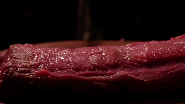Raw beef tenderloin on a wooden board. Slider. Marbled meat. Dark atmosphere