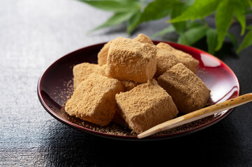 Warabi mochi placed on a black Japanese tray.