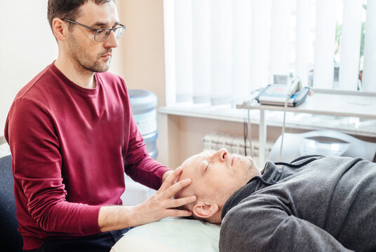 Male Patient Receiving Cranial Sacral Therapy, Lying On The Massage Table In CST Osteopathic Clinic, Osteopathy And Manual Therapy