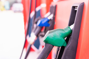 Close up green fuel nozzle on tank of gas station in commercial gas station to filling power oil energy into car for transportation with copy space in frame