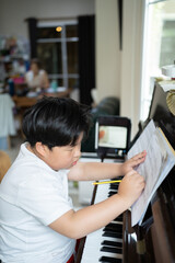 Obraz premium A boy is studying piano online with tablet.