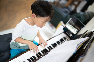 A boy is studying piano online with tablet.