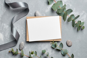 Invitation or greeting card with fresh eucalyptus twigs on grey concrete background