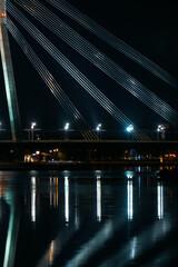 View of part of the bridge at night with a reflection in the river