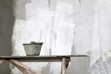 Bucket on a work bench on a construction site against a blank white painted concrete wall