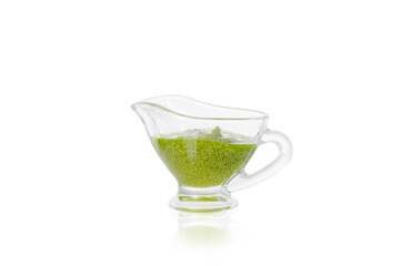 Delicious, fresh pesto sauce made with basil, olive oil, garlic and pine nuts. Green pesto sauce in a gravy boat on a white background.