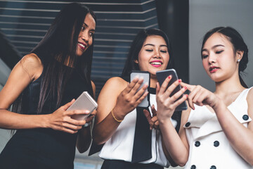Three women friends having conversation while looking at mobile phone in their hands. Concept of...