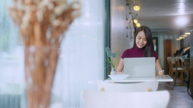 young attractive asian female wear casual cloth hand use smartphone and laptop device comminication social contact in cafe restaruant sit at counter next to big window daylight