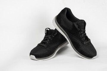 Sneakers for boys or girls, unisex, on a light background. Sporty black sneakers with a light comfortable sole