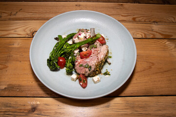 A delicious plate of Spring Lamb chops with spring vegetables on a wooden kitchen table