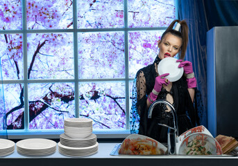 The girl in the kitchen licks the dirty dishes with her tongue