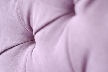 Selective focus texture of velour sofa with buttons. Fabric surface of furniture is pink. Interior with furniture. Concept of comfort and coziness.