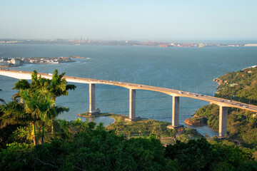 aerial view of the bridge over the sea and city and tropical trees