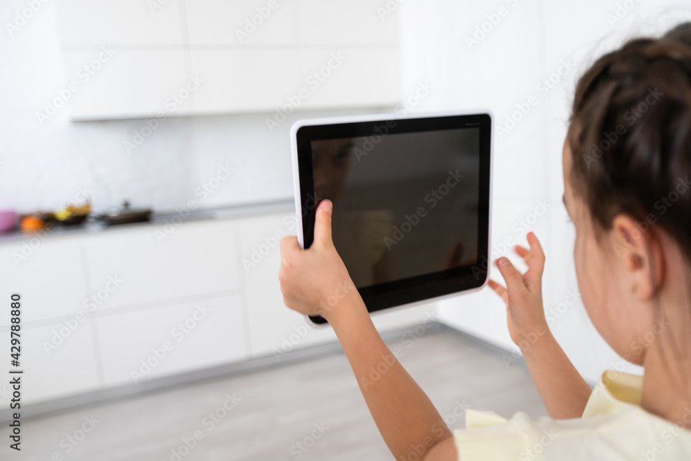 Poster shot of little girl using a domotic system with her digital tablet while standing at home.