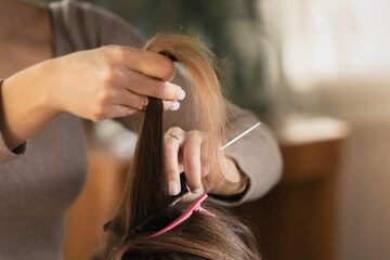 A lock of brown hair and hairbrush in the hands of a barber master. The concept of a hairdresser,...