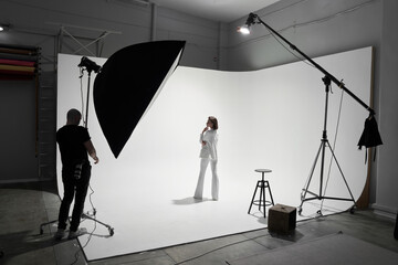 Fashion photography in a photo studio. Professional male photographer taking pictures of beautiful...