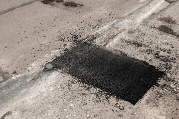 Cracked asphalt road surface and repair patch closeup