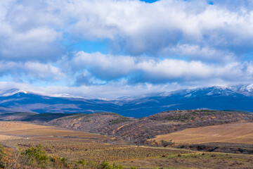 Panoramic view of the mountains. Spring vineyards and forests near the mountains and blue mountains covered with snow on the horizon