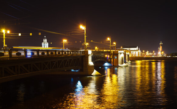St. Petersburg at night. View of the Palace Bridge, the Neva River with color reflection and the embankment of Vasilievsky Island with Rastral Columns. Beautiful evening cityscape