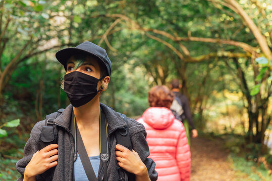 hiker with face mask to protect himself from coronavirus hiking through a forest. mountain activities in the new normal