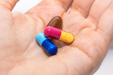 Close-up colorful powder soft capsules pill in hand. blue pink yellow brown medicine supplement vitamin