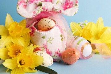 Colored Easter eggs in decorative basket and a bouquet of yellow narcissus