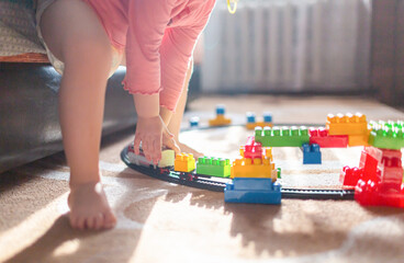 Toddler child girl in a diaper plays in room with train toy.