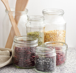 Variety of dry legumes: kidney bean, peas, green gram in glass jars uncooked on white kitchen background, zero waste, eco friendly, balanced diet food, healthy clean eating, vegan protein concept