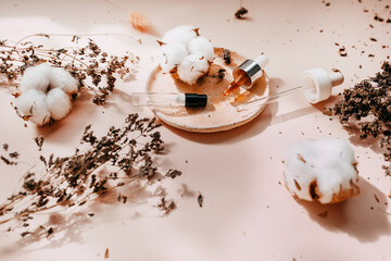 Cosmetic pipette bottles with essential oils, natural herbs and cotton. Natural skin care, serum and cosmetic products on a saucer. Flat lay