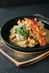 Delicious lunch, hot dish with mushrooms, potatoes and fried bacon. A hearty dinner. Beautiful still life, photo for the restaurant menu