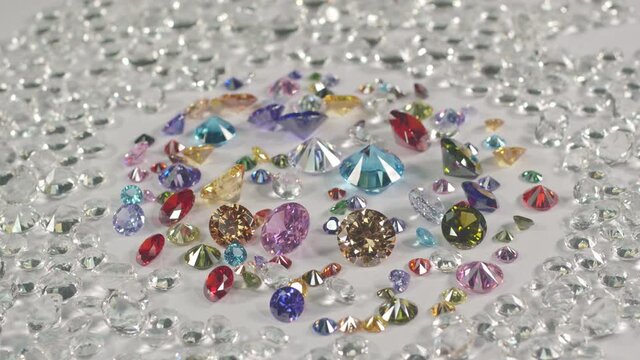 colorful gemstones are placed on white floor with white diamonds background..high quality video shot with video with BMPCC 6K in studio.