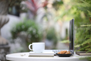 White coffee cup and laptop side view with cookies
