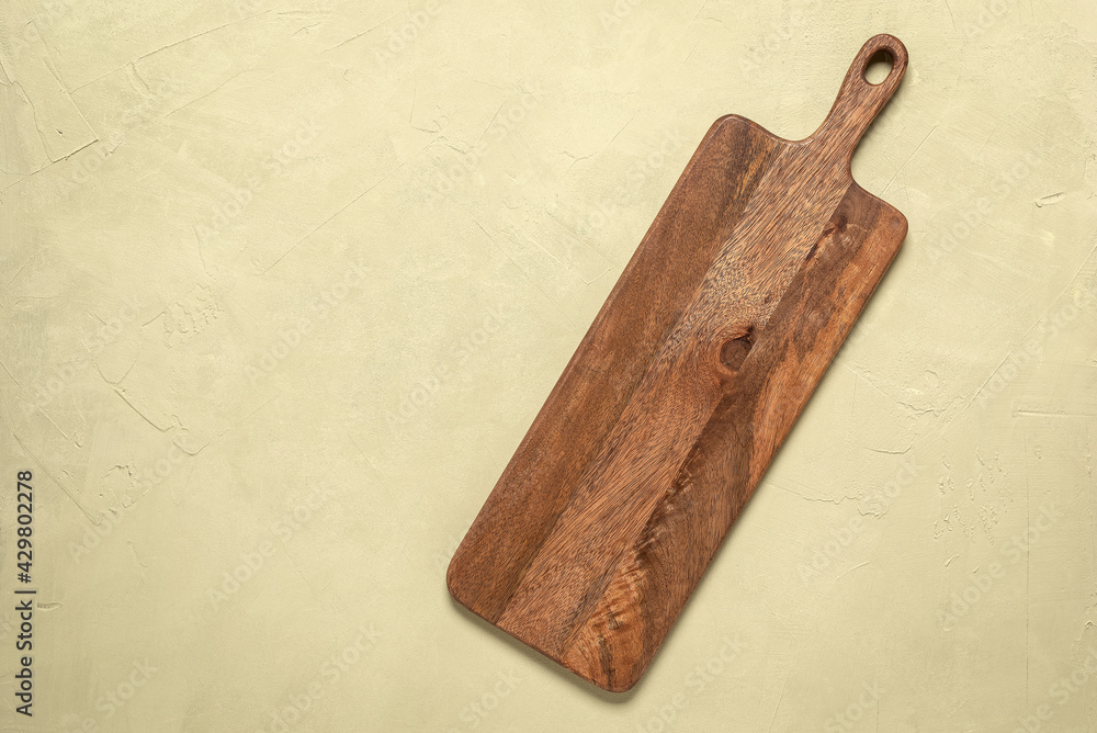 Wall mural wooden long empty cutting board on a beige concrete background. top view, flat lay.