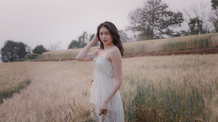Fototapeta na wymiar young asian girl in white dress walking relax in barlay field