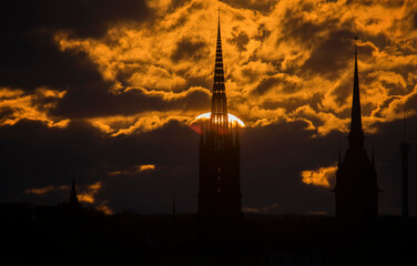 Morning skyline of the old town Gamla Stan at spring equinox at sunrise. Orange clouds over the Stockholm archipelago