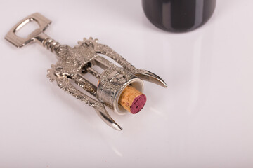 Red wine bottle, cork stopper and an italian prestigious corkscrew on a white background