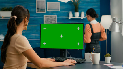 Beautiful caucasian woman working on green screen mock up PC with chroma key while her apartment...