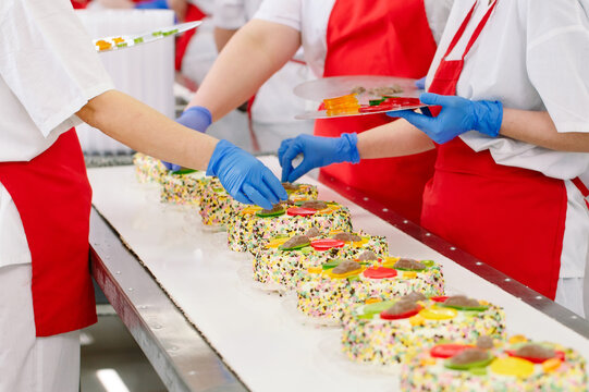 Decorating cakes on the conveyor of a confectionery factory.