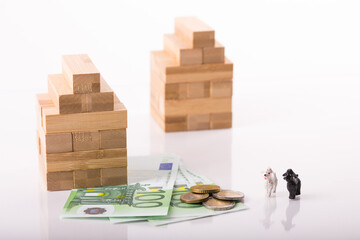 Wooden house, 100 euros banknotes and coins white background. Concept for real estate market