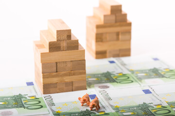 Wooden house, 100 euros banknotes and white background. Concept for real estate market