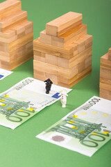 Three houses, three 100 euros banknotes and green background. Concept for real estate market