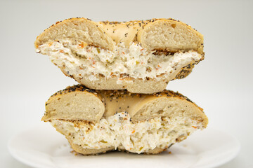 New York City Everything Bagel Cut in Half and Filled with Olive and Feta Cream Cheese on a White Plate