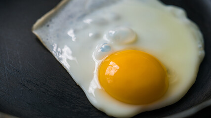 The egg is fried in a frying pan without oil. Healthy breakfast. Close-up.