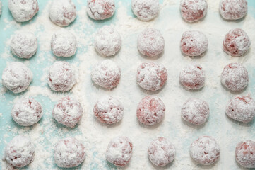 Meat balls covered with flour lie on the surface. The cooking process. Tasty food. View from above.