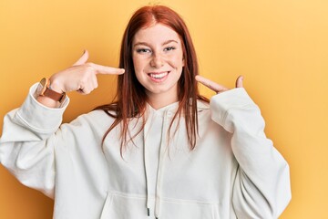 Young red head girl wearing casual sweatshirt smiling cheerful showing and pointing with fingers teeth and mouth. dental health concept.