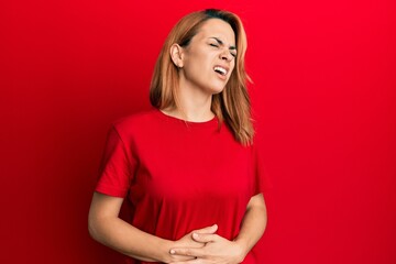 Obraz premium Hispanic young woman wearing casual red t shirt with hand on stomach because nausea, painful disease feeling unwell. ache concept.