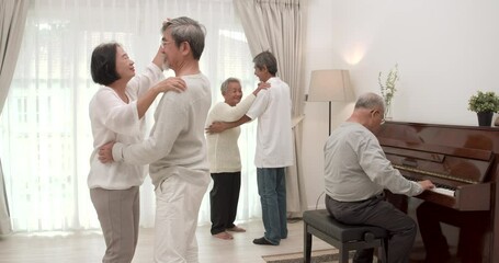 A happy Asian old man playing a song on piano and the other of seniors male and female having fun and dancing with happy emotion together in common room at nursing room. Relaxation concept. - Powered by Adobe
